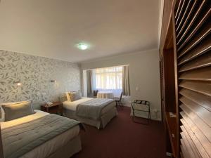 a hotel room with two beds and a window at Hotel Nicolás Temuco in Temuco