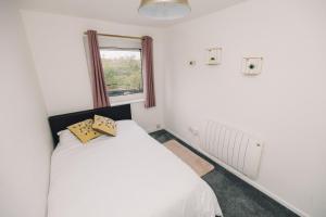1 dormitorio con cama blanca y ventana en Luxe Spacious & Central 2Bed Luton Apartment - Free Parking - Free Wi-Fi - Near LTN Airport & L&D Hospital en Luton