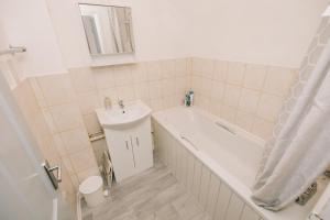 a bathroom with a white tub and a sink and a toilet at Luxe Spacious & Central 2Bed Luton Apartment - Free Parking - Free Wi-Fi - Near LTN Airport & L&D Hospital in Luton