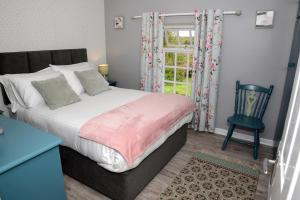 a bedroom with a bed and a chair and a window at Cloverhill Gate Lodge in Cloverhill