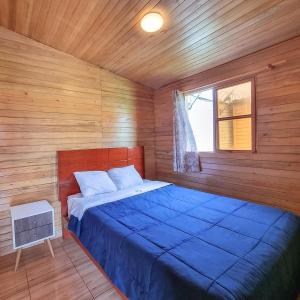 a bedroom with a blue bed in a wooden room at Apart Hotel El Paraíso de Barranca in Barranca