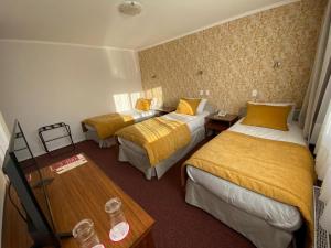 a hotel room with three beds and a table at Hotel Nicolás Temuco in Temuco