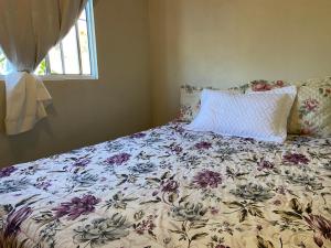 a bed with a floral comforter and a pillow at Casa da Vila Pousada in Três Coroas