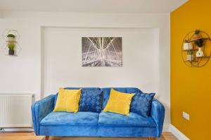 Sofá azul en la sala de estar con almohadas amarillas en Sleeps 5 - Large Garden - Wifi en Kent