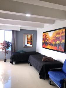 um quarto com duas camas e um quadro na parede em Apartamento totalmente equipado a media cuadra de la playa del Laguito em Cartagena das Índias
