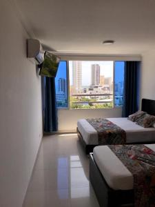um quarto de hotel com duas camas e uma grande janela em Apartamento totalmente equipado a media cuadra de la playa del Laguito em Cartagena das Índias