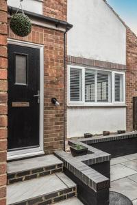 a brick house with a black door and two windows at Seascape - Modern one bedroom, two storey annexe in Kent