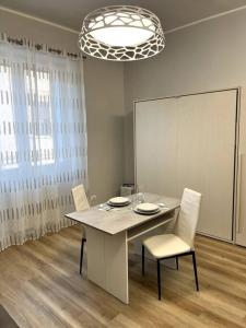 une salle à manger avec une table, des chaises et un lustre dans l'établissement Grano - appartamento Lecce centro, à Lecce
