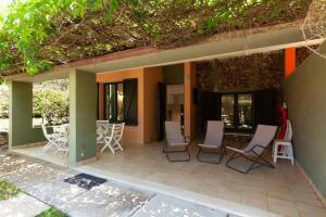 un patio con sillas blancas, mesa y ventanas en [Villasimius] 5 Min. dal mare, en Oasi dei Due Mari