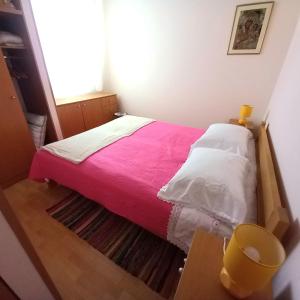 a small bedroom with a bed with a pink blanket at Kat's - Roman Salona in Solin