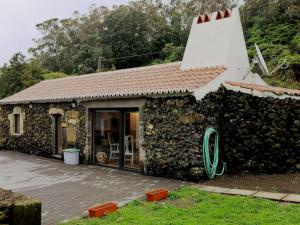 a stone house with a green hose outside of it at Ti Chôa - Casa da Mata in Angra do Heroísmo