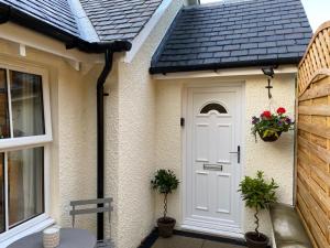 a white door of a house with flowers on it at Buccleuch Garden Room in Fort William