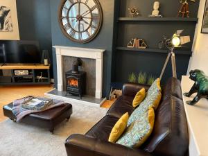 a living room with a leather couch and a fireplace at 34Three in Lytham St Annes