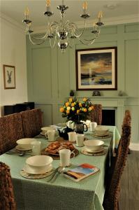 a dining room table with a green table cloth and flowers at Serendipity in Kirkcudbright