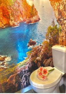 uma casa de banho com uma pintura do oceano e um WC em Cap d'Agde Naturiste Port Nature 90 em Cap d'Agde