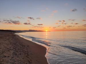 una puesta de sol en una playa con el océano en Sardinian Seaside Retreats, en Badesi
