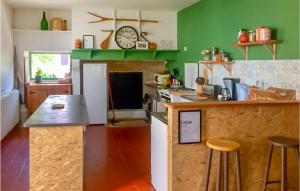 una cocina con paredes verdes y una barra con taburetes en 3 Bedroom Awesome Home In Sault-de-navailles en Sault-de-Navailles