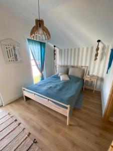 a bedroom with a bed with blue sheets and a window at Dwupiętrowy Apartament Latarnik - Jastrzębia Góra in Tupadły