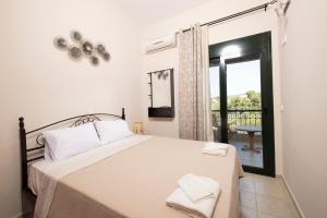 a bedroom with a bed with white sheets and a window at Villa Aliki in Pefkohori