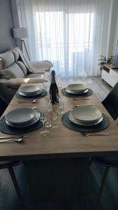a wooden table with plates and wine glasses on it at Dreams Apartment Vilafortuny in Cambrils +38 photos