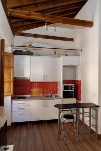 cocina con armarios blancos y mesa negra en Puerta Real Luxury Apartments Granada, en Granada
