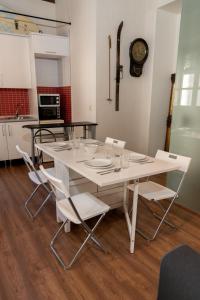 mesa de comedor blanca con sillas blancas y reloj en Puerta Real Luxury Apartments Granada, en Granada