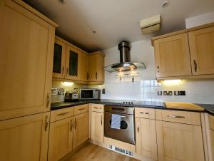 een keuken met houten kasten en een fornuis met oven bij Quayside apartment with riverside views & parking in Newcastle upon Tyne