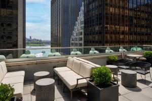 uma varanda com cadeiras e mesas e vista para a cidade em The Wall Street Hotel New York City em Nova Iorque