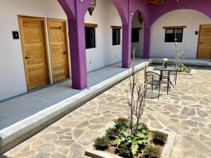 un patio con columnas púrpuras, mesa y sillas en Hostal de la Montaña, en Mazamitla