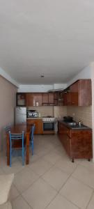 una cocina con armarios de madera, mesa y sillas en Family Residence en Shëngjin