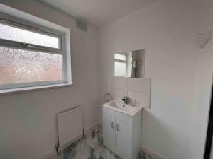 a white bathroom with a sink and a window at Homely 4 bed quiet neighbourhood w/ huge driveway in Lemington