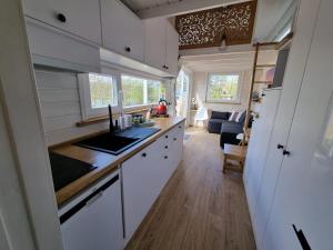 a kitchen with white cabinets and a living room at Domek nad jeziorem z jacuzzi in Sulęczyno