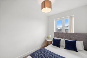 a bedroom with a bed with blue pillows and a window at Luxnightzz - Clarendon Heights - Stylish Two-Bedroom Apartment in Colchester