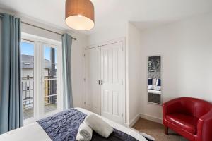 Un dormitorio con una silla roja, una cama y una ventana en Luxnightzz - Clarendon Heights - Stylish Two-Bedroom Apartment, en Colchester