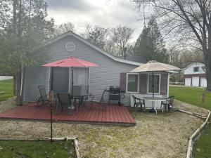 a house with a deck with a table and umbrella at Fun Lake House on Long Lake near beaches home in Campbellsport