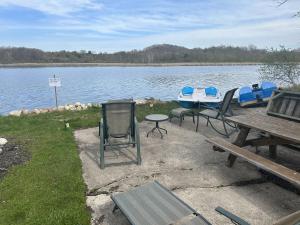 a picnic table and chairs next to a lake at Fun Lake House on Long Lake near beaches home in Campbellsport