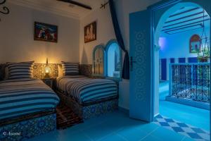 a bedroom with two beds and an open door at Dar Qaysar in Chefchaouene