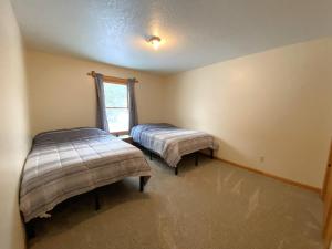 two beds in a room with a window at North Country Retreat in Saint Ignace
