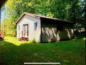 a small house in a grassy yard with a porch at North Country Retreat in Saint Ignace