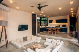 a living room with white couches and a kitchen at Round Villa Private Pool & Jungle rooftop 2A in Tulum