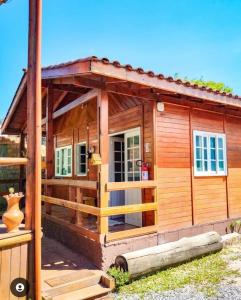 eine kleine Holzhütte mit einer Veranda in der Unterkunft Pousada - Quintal do Rosa in Praia do Rosa
