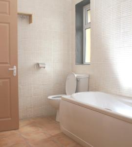 baño con bañera, aseo y ventana en Charming Two Bedroom Cottage with Magnificent Sea Views. 10 minutes from Kenmare, en Kenmare