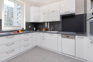 a white kitchen with white cabinets and a window at Gdańsk Aleja Jana Pawła II Apartment with Parking and Balcony by Renters in Gdańsk