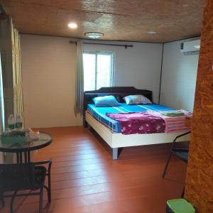 Un dormitorio con una cama y una mesa. en บ้านสวนริมน้ำวังใหญ่2 วังสามหมอ อุดรธานี 
