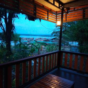 una veranda in legno con vista sull'oceano di บ้านสวนริมน้ำวังใหญ่2 