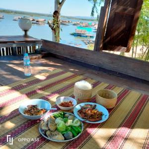 una tavola con piatti di cibo e vista sull'acqua di บ้านสวนริมน้ำวังใหญ่2 