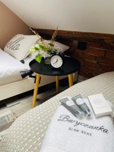 een tafel met een klok erop naast een bed bij Baryczanka SLOW HOME in Przygodzice
