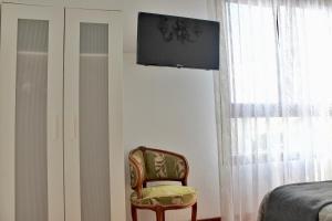 1 dormitorio con silla y TV en la pared en A Estribor - 20001, en Argoños