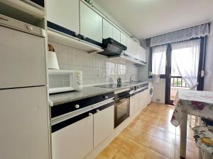 a kitchen with white cabinets and a white microwave at A Estribor - 20001 in Argoños
