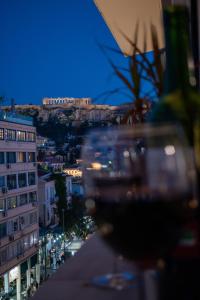 a glass of wine on a table with a view of a city at AcroView Right In The Center in Athens